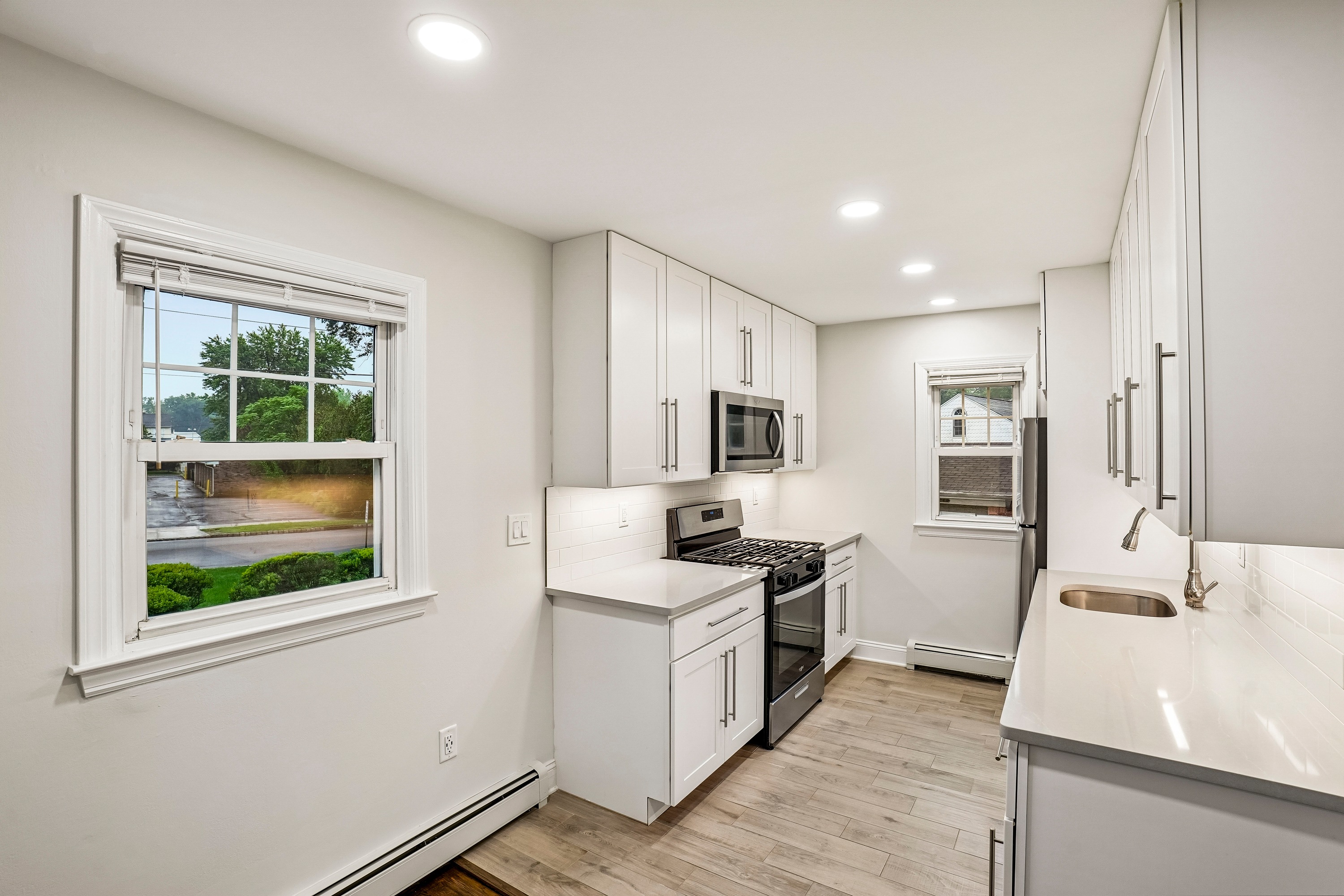 A white kitchen with a window overlooking a street.